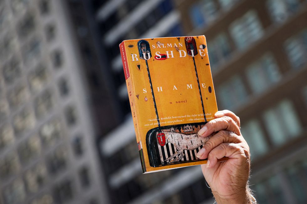 Un hombre sostiene un libro del autor Salman Rushdie, mientras asiste a una concentración en defensa de la libertad de expresión en la Biblioteca Pública de Nueva York, el 19 de agosto.BRENDAN MCDERMID