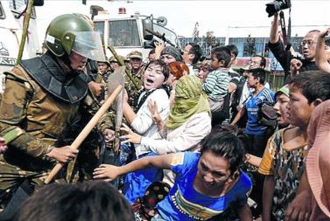 Unas mujeres uigures tratan de romper un cordón policial, ayer. / AFP / PETER PARKS