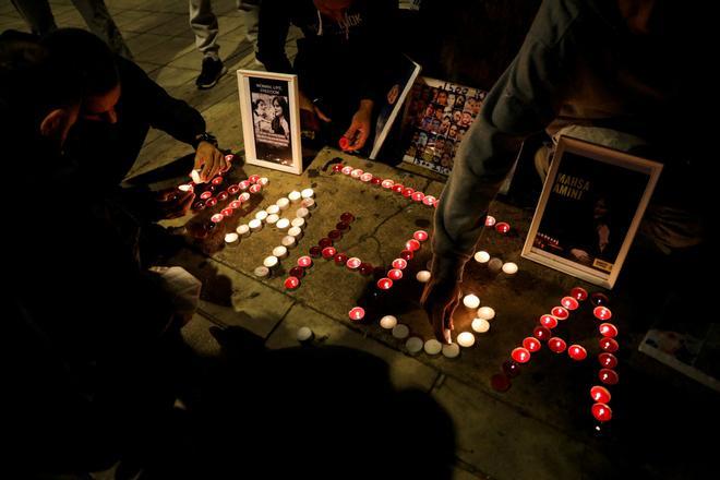 Varias personas encienden velas en un homenaje a la joven iraní Masha Amini.