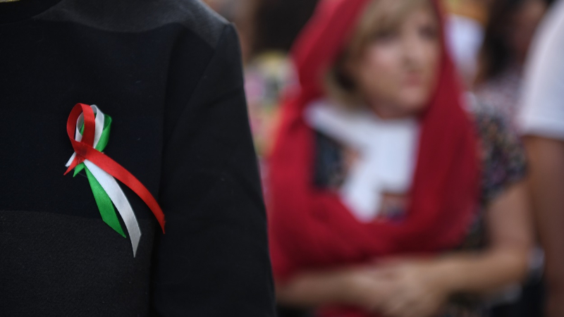 Una persona se coloca un lazo con la bandera de Irán en una concentración contra la muerte de dos mujeres iraníes.