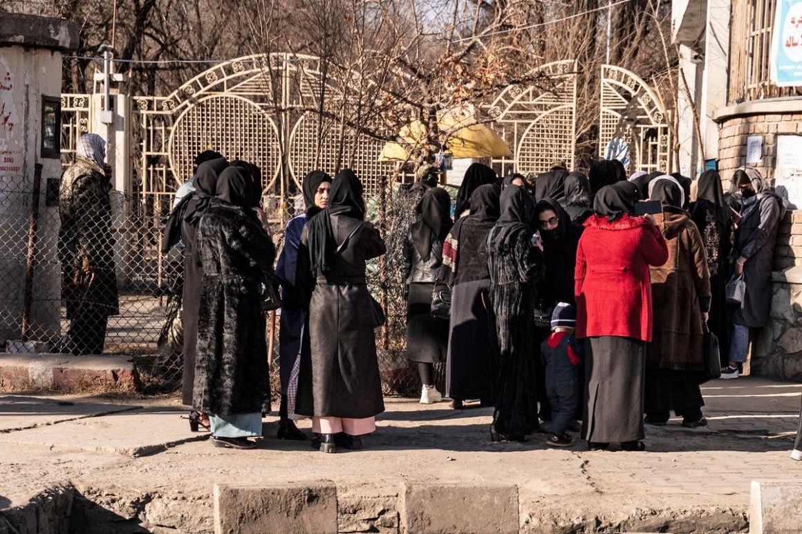 Mujeres afganas en la puerta de la universidad, custodiada por soldados, en Kabul. / ALI KHARA / REUTERS