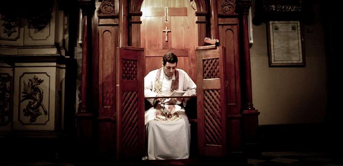 Sacerdote en un confesionario. Imagen de archivo.