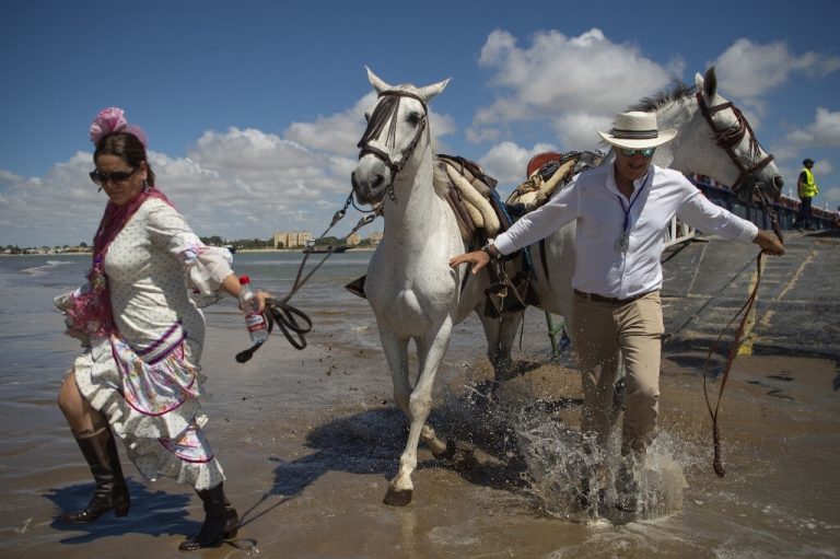 Los peregrinos cruzan el río Guadalquivir en ruta hacia el santuario de El Rocío en el parque nacional de Doñana durante la peregrinación anual de El Rocío.- AFP