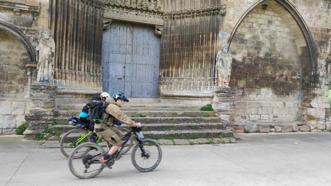 Dos peregrinos en bicicleta pasan por delante de la portada del Santo Sepulcro en Estella-Lizarra Javier Arizaleta