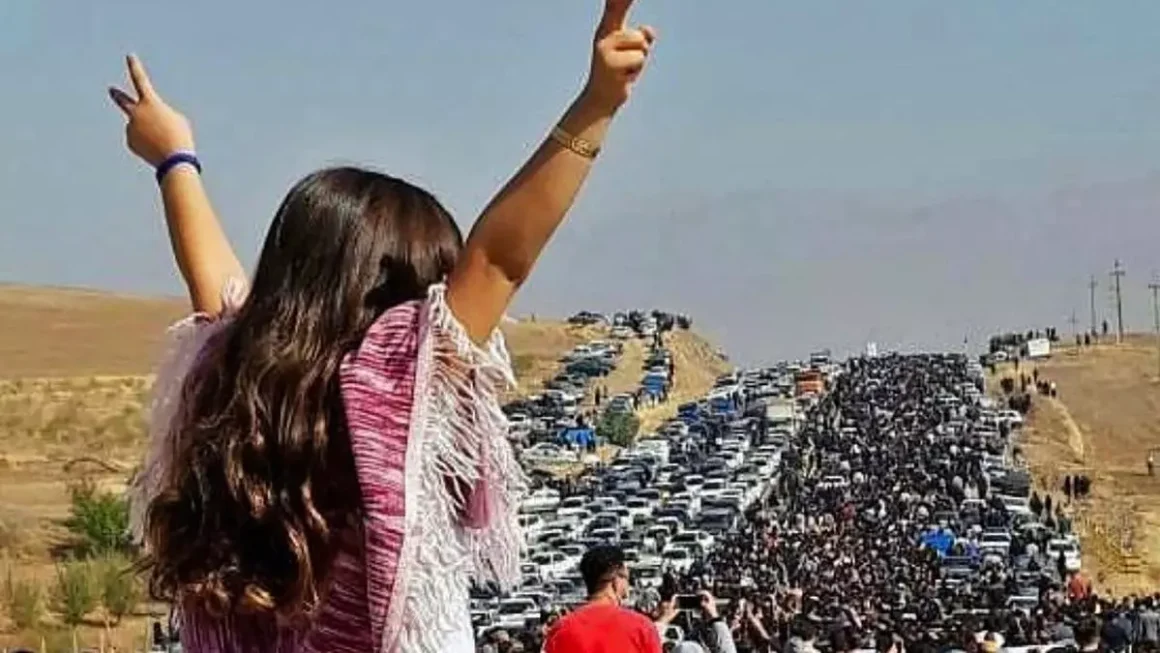 Una mujer sin velo en la parte superior de un vehículo mientras miles de personas se dirigen hacia el cementerio de Aichi en Saqez, la ciudad natal de Mahsa Amini en la provincia occidental iraní de Kurdistán, para conmemorar los 40 días desde su muerte. / AFP