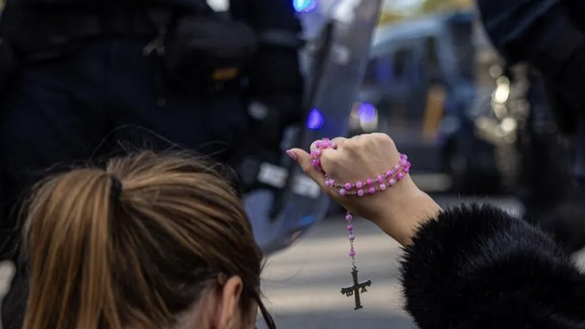 Una mujer con un rosario en las protestas contra el PSOE en la calle Ferraz. EFE