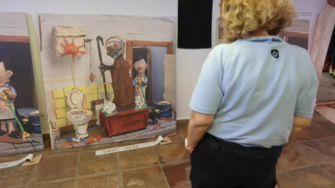 Una persona observa la imagen en que una caricatura de Sant Pere orina en un retrete. / TONI LOSAS