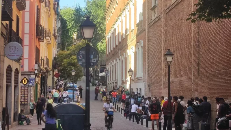 Colas en el comedor social de la Hermandad del Refugio, en Madrid, con una tienda de 'pancakes' a la izquierda. Somos Madrid